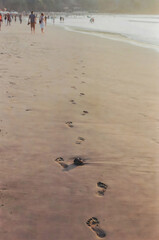 View of human foot trail on sand at beach in Jimbaran, Bali at sunset.