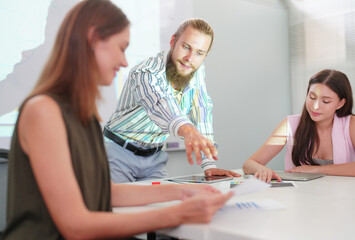 Young office worker presenting new financial plan to his partners during a meeting
