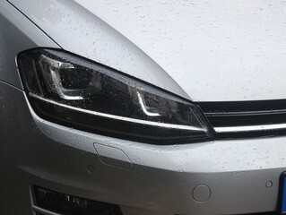 Silver crossover vehicle headlight in the rain.  © Noah