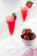 Tall champagne glasses filled with strawberry Mimosas, ready for drinking.