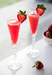 Refreshing strawberry Mimosas on a table against a sunny window.