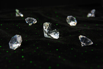glass diamonds in green laser light. The gemstones in different sizes lie on black velvet.