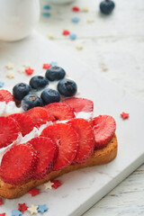 4th of July American Independence Day food. American flag sandwich with strawberries, blueberries, whipped sweet cream, soft cheese on toast bread. Independence or Patriotic Day breakfast idea Mock up