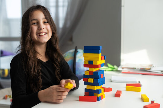 Children building wood blocks at playground. Girl kid playing stacking wood blocks (Jenga games) for meditation practice. Hand movement control Building Computational Skills Children's play concept.