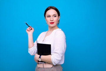 Naklejka premium Portrait of a successful business woman with a notebook on a blue background in the studio