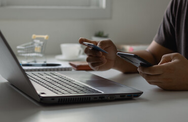 Fototapeta premium Online shopping concept. Customer makes a purchase on the Internet on a smartphone with a credit card, online payment, shopping online, e-commerce, internet banking, and spending money.