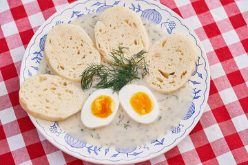 Top view on the rustic vintage blue onion porcelain plate with traditional Czech bread dumplings in dill sauce and boiled egg. Fresh, healthy, seasonal example of traditional recipe of Czech cuisine.