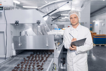 Chocolate factory worker inspecting production line conveyor with sweets candy. Concept food...