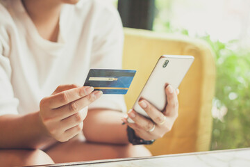 Woman hand using smart phones and holding credit card for shopping payment online, or for business, finance, and payment concepts. - obrazy, fototapety, plakaty