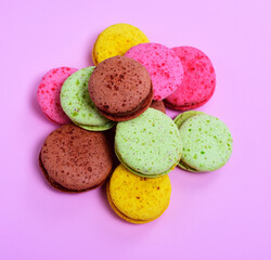 bunch of multicolored macaroons on a pink background, top view