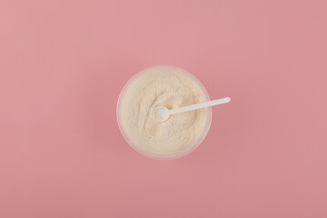 Food additive E415. Xanthan Gum Powder in plastic bowl with measuring spoon, top view. Binding agent, Gluten free ingredient. Pink background, copy space