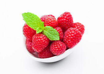 Fresh healthy red raspberries in white bowl with mint leaf on white background.