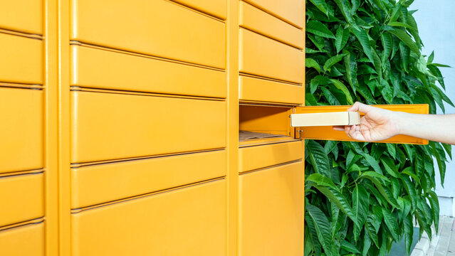 Hand picking up an order at an Amazon locker. Convenient and fast deliveries of shopping online. Copy space. Seville, Spain; 06-20-2023.