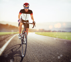 Fototapeta premium Front view of a road cyclist in uniform during a race at sunset