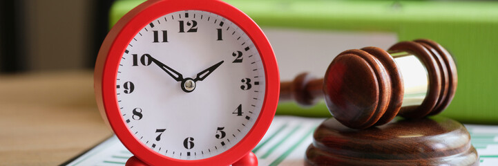 Judges hammer with red alarm clock on clipboard