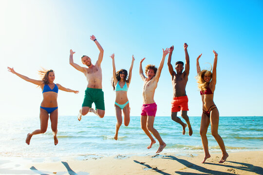 Happy group of friends jumps together on the seashore