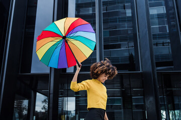 young African American woman homosexual with rainbow flag or umbrella in city of Latin America, Hispanic and caribbean LGBT female with afro hair