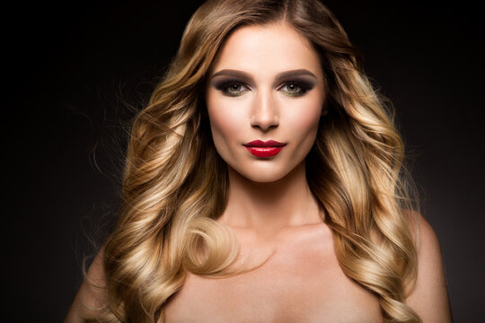 Beautiful blonde model girl with long curly hair . Hairstyle wavy curls . Red lips . Fashion , beauty and make up portrait