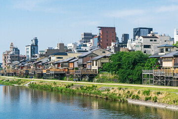 Fototapeta na wymiar Urban or tourism east-Asian background featuring city skyline with vintage buildings of Kyoto, Japan, on a bank of Kamo river in sunny day in summer.