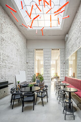Restaurant with light textured walls and a large window on the ceiling. There are red and gray...