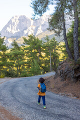 a child with a backpack goes along a mountain road. children's trip. weekend with kids. adventure and hike.