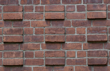 decorative red brick wall, running bond interspersed with protruding pairs of stacked bricks create a cubic geometric design background