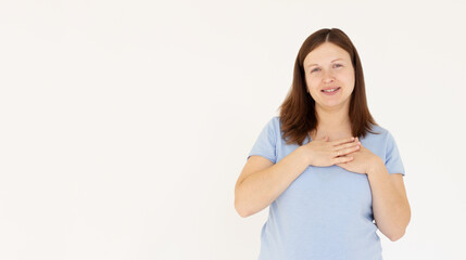 Close up of happy smiling woman say thank you, holding hands on heart grateful, express gratitude, standing against white background.