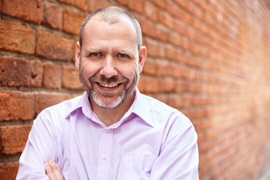 Portrait of smiling man against a brick wall background.