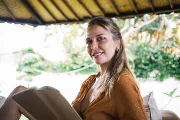 Smiling woman with book on terrace