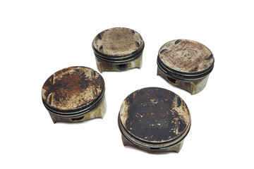 engine pistons set of four. worn out change part of old car motor. surfaces in burnt oil and black sludge. isolated on white background, with clipping path