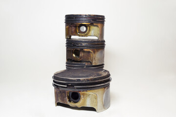 engine piston in black sludge and burnt oil, with removed oil control ring, closeup. pile of...