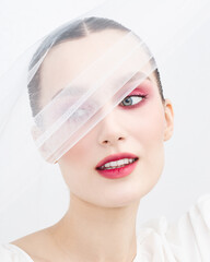 Woman with creative makeup in white veil on white background. International Women's Day