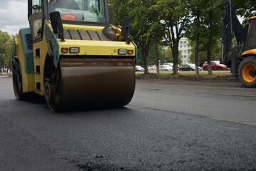 A road roller compacts the asphalt mortar on the road to be repaired.