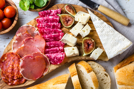 Antipasto olive wood board with salami, ham serrano, cheese, nuts and ciabatta bread