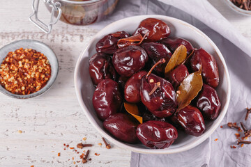 Bowl of pickled plums with spices on rustic wooden background. Clean eating, vegetarian food concept