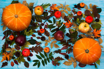 Thanksgiving  greeting with pumpkin, apples and autumn leaves on blue wooden table. Fall background...