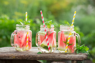 Fototapeta na wymiar Watermelon water in glass jars in the open air. Concept for healthy eating and nutrition.