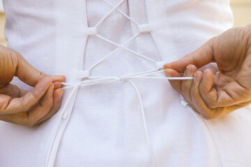 Girl tightening laces on the back of her dress.