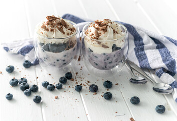 Dessert from yogurt with blueberries and chocolate on a white wooden background