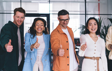 Group of cheerful male and female colleagues showing OK during working day for collaboration...