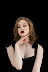 Studio portrait of beautiful redhead woman with freckles wearing black dress on dark background