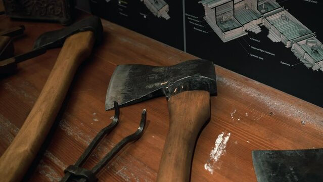 Analysis of items for repair. Media. Huge axes and iron keys that lie on the table next to the wall charts.