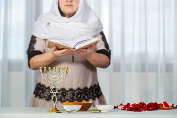 A Jewish woman in a white headscarf reads Tehillim before the wedding for a happy family life.