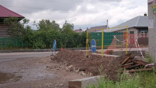 Repair of pipes on village road. Clip. Detour signs at pit on road. Landscape of village road with pits and detours