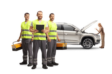 Team of road assistance workers with reflective vests standing in front of a woman with a broken down SUV