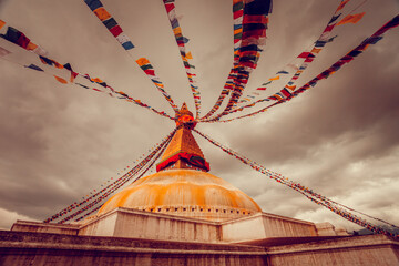 The famous Buddhist stupa at Boudanath in Kathmandu valley, Nepal. Was built in the 14th century. Dranatic cloudy sky in the background. Travel, holidays. Vintage retro toning filter orange color