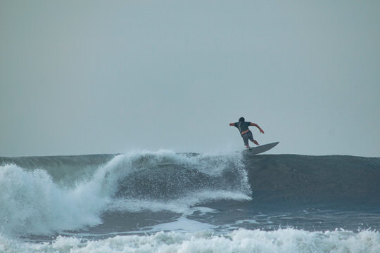Boy surfing the wave at the paredon beach in the summer