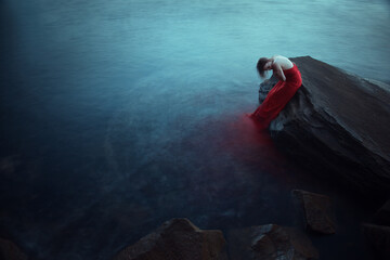 Lonely woman in red dress near the sea