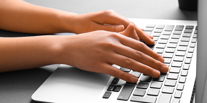Hands of woman using laptop, closeup