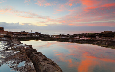 Sunrise at Wollongong Harbour with beautiful reflections in natural rock pool.  A fisherman on the far rocks